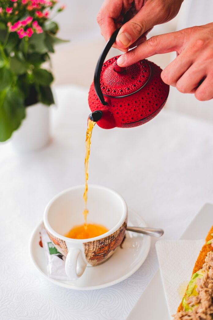Photo by Frames For Your Heart person pouring red liquid on white ceramic teacup