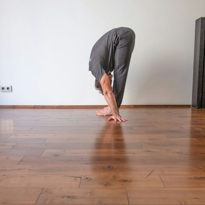 Photo by GMB Fitness a man doing a handstand on a hard wood floor