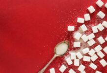 “설탕 대신 먹었는데”… 제로 열풍의 주역 ‘알룰로스’의 배신? 오해와 진실 sugar cubes and a spoon on a red surface