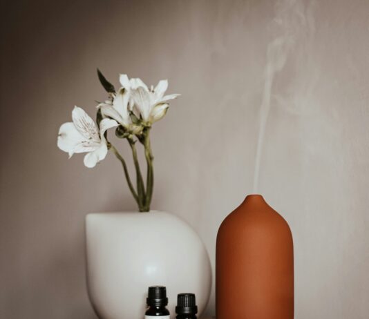 “수면, 바꿔야 할 생활습관의 시작…지금 바로 실천할 수 있는 건강 수면 루틴” a vase with a flower and two bottles of essential oils on a table