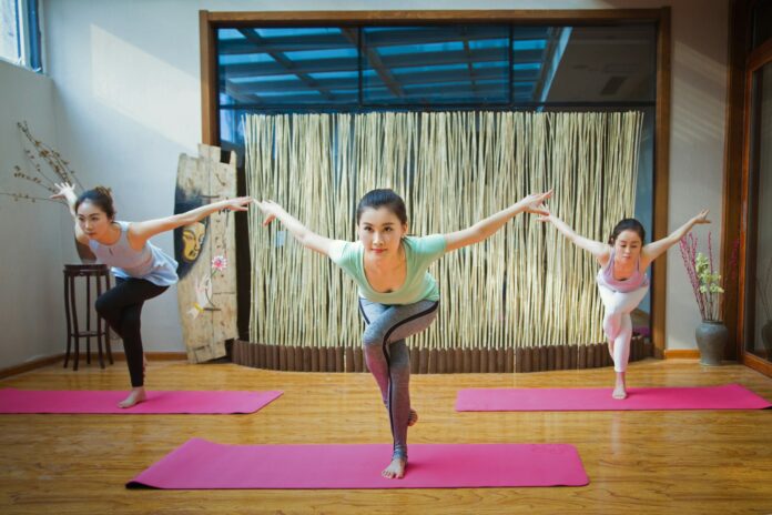 Photo by Alex Shaw 2 women in pink tank top and pink leggings doing yoga