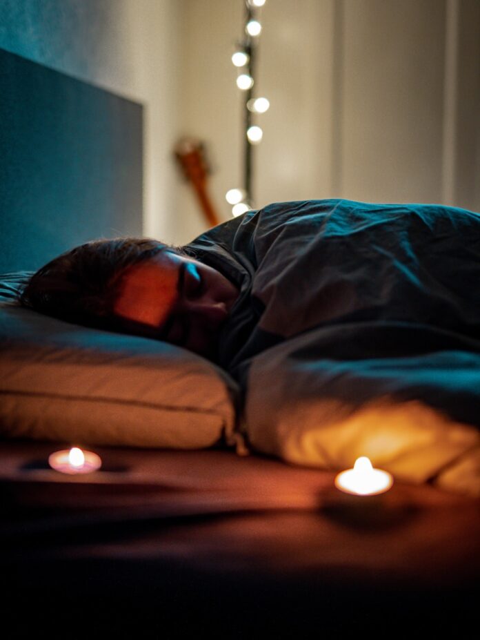 Photo by iwin a person sleeping on a bed with some candles