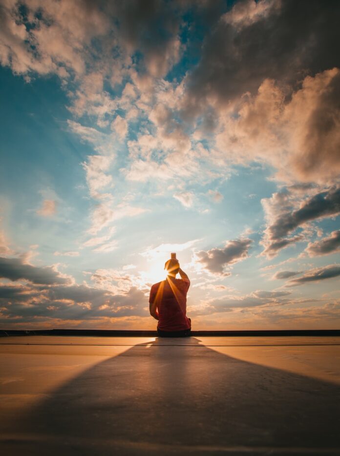 Photo by Josh Hild person sitting and facing back under blue and white sky